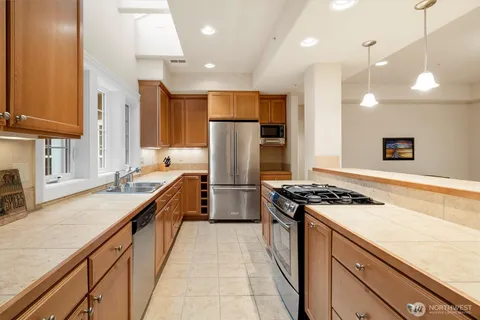 a kitchen with stainless steel appliances granite countertop a sink a stove and a refrigerator