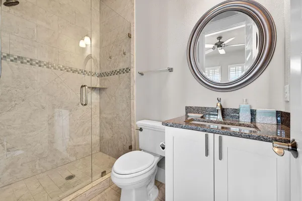 a bathroom with a granite countertop toilet a sink and a mirror