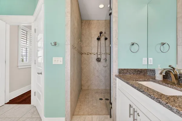 a bathroom with a granite countertop sink two mirror and shower