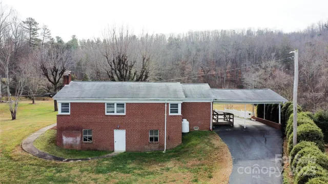 an aerial view of a house with yard and trees in the background