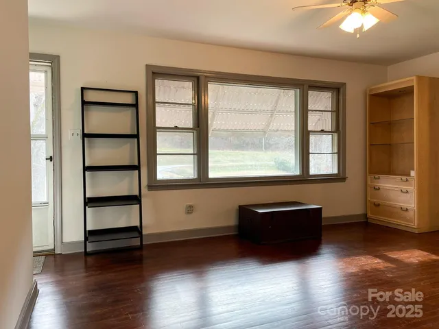an empty room with wooden floor closet and windows