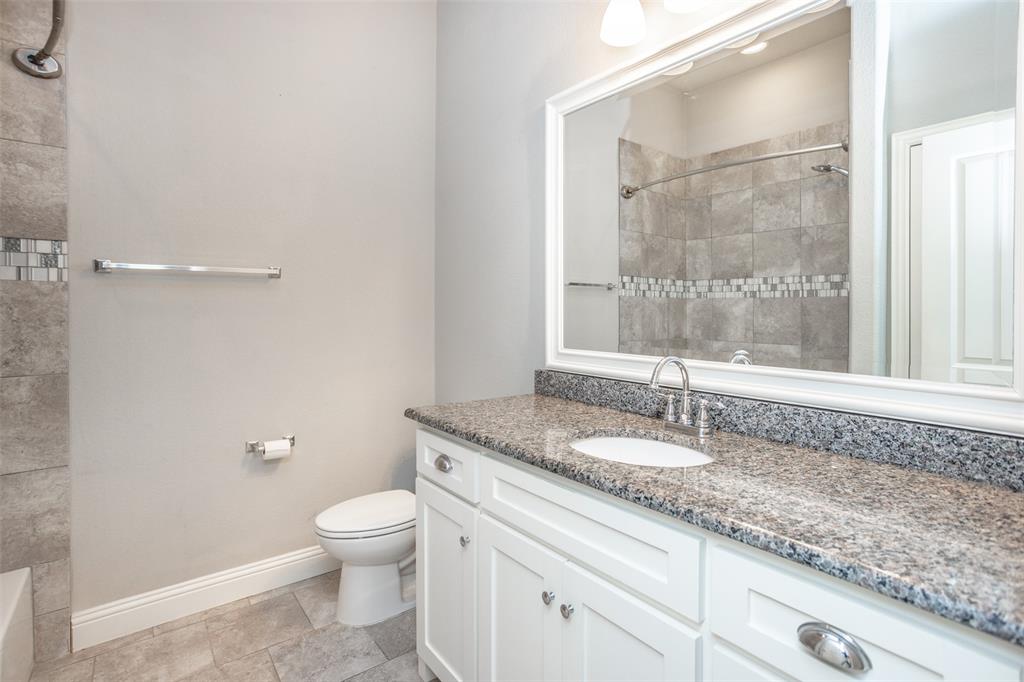 702 La Paloma Road Sanger, TX 76266 - Photo 34 of 40 a bathroom with a granite countertop sink a toilet and a mirror