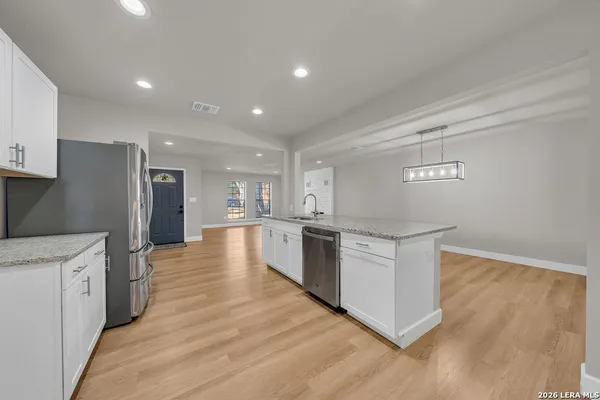 a large kitchen with stainless steel appliances granite countertop a large counter top and wooden floors