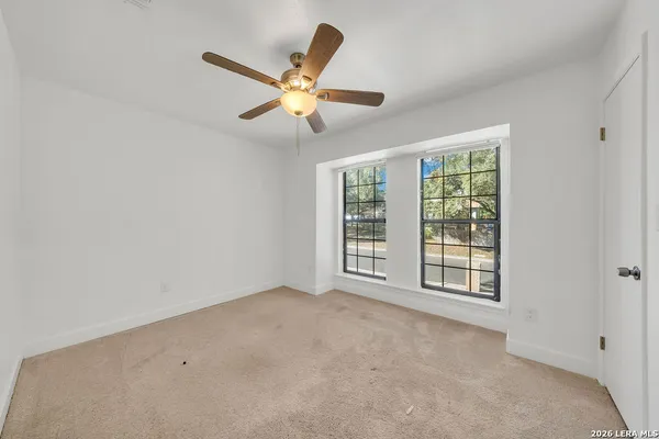 an empty room with windows and fan