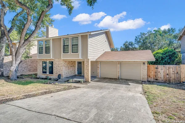 a view of a house with a yard and large tree