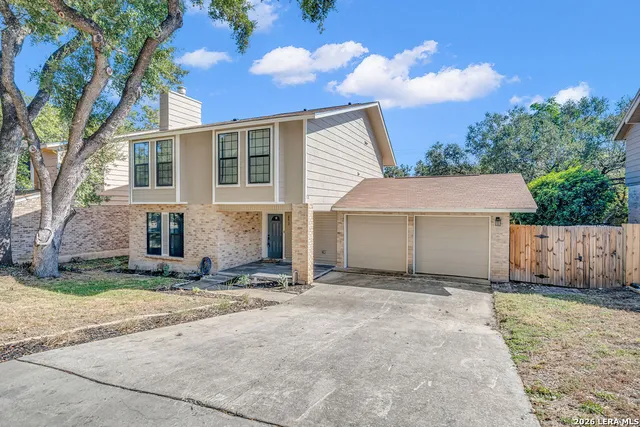 a view of a house with a yard and large tree