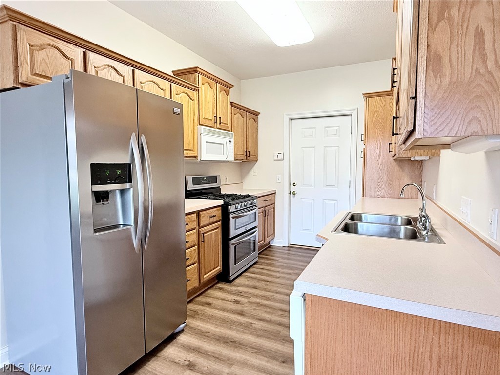 603 South Raccoon Road, Unit 1 Austintown, OH 44515 - Photo 7 of 22 Kitchen featuring wood cabinetry, stainless steel appliances, a double basin sink, light-toned countertops, and wood-finish flooring