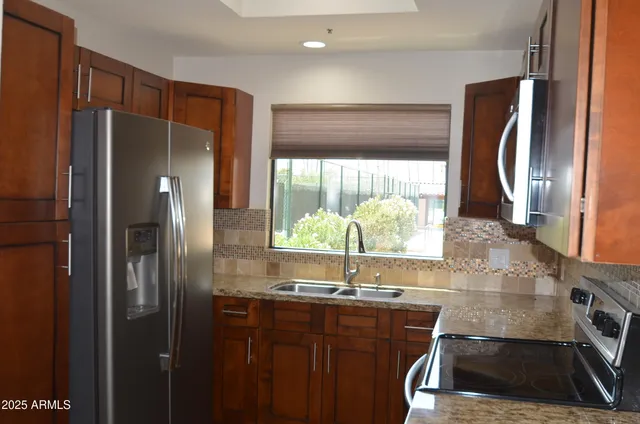 a kitchen with stainless steel appliances granite countertop a refrigerator and a sink