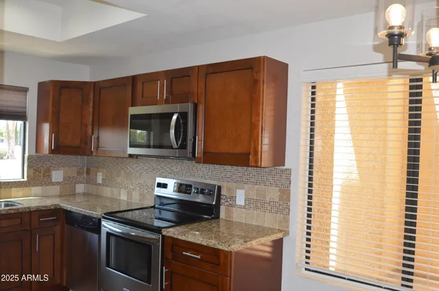 a kitchen with stainless steel appliances granite countertop a stove a sink and a microwave
