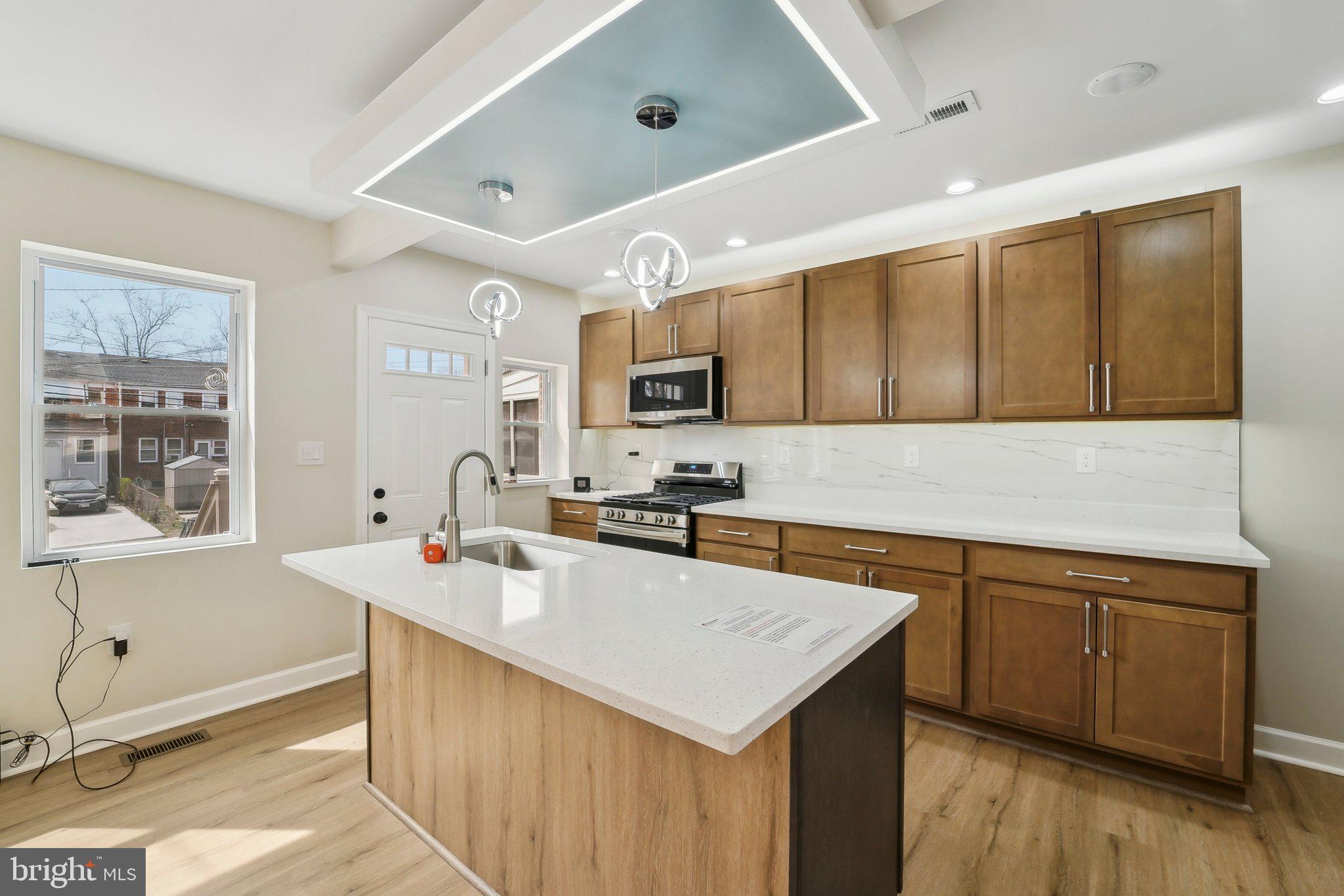 2920 Cornwall Road Dundalk, MD 21222 - Photo 2 of 38 a kitchen that has a sink a microwave oven a stove and white cabinets with wooden floor