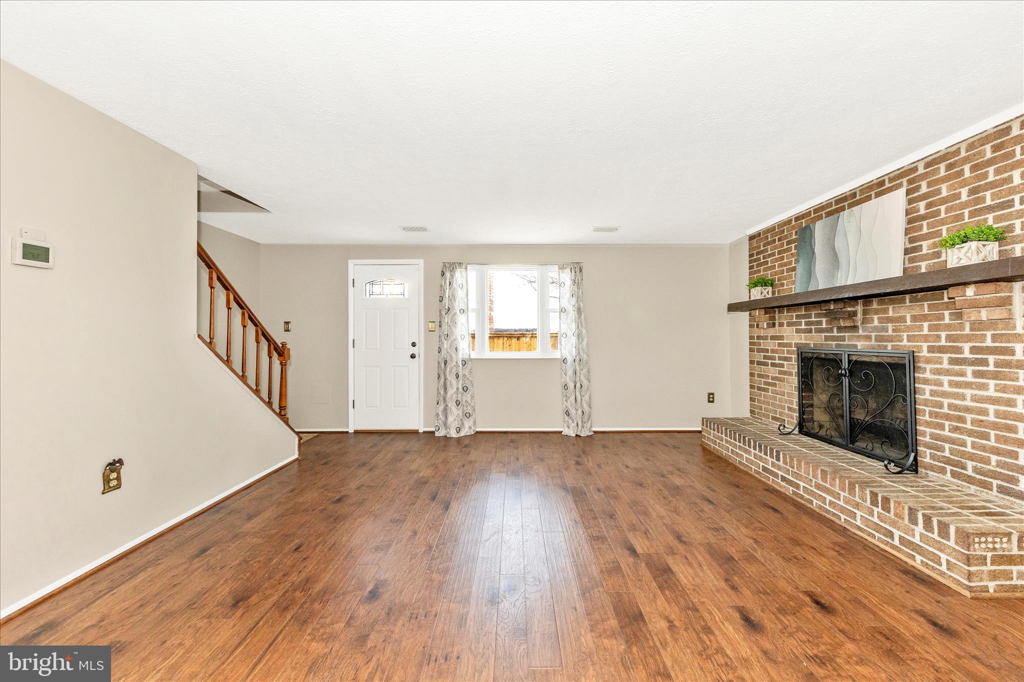 6616 Pebble Court Frederick, MD 21703 - Photo 11 of 33 a view of an empty room with wooden floor fireplace and a window