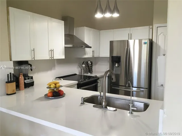 a kitchen with stainless steel appliances granite countertop a sink refrigerator and cabinets