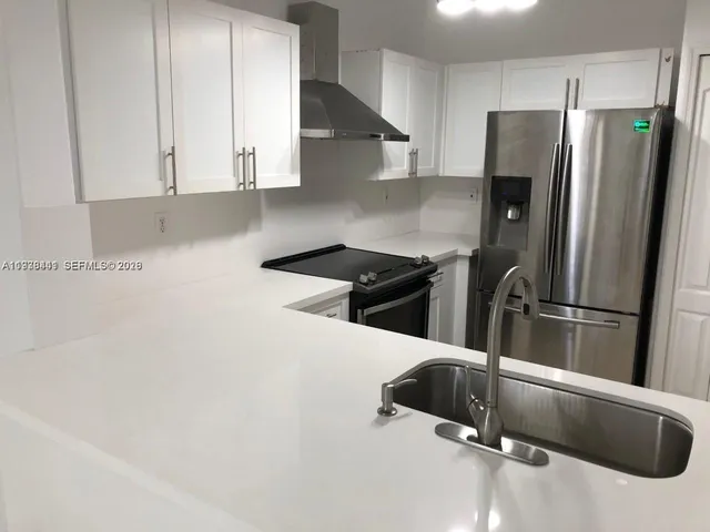 a kitchen with granite countertop a refrigerator and a sink