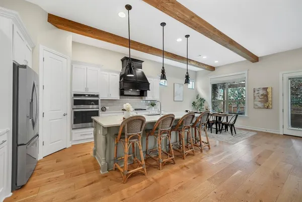 a kitchen with stainless steel appliances kitchen island granite countertop a table chairs sink and cabinets
