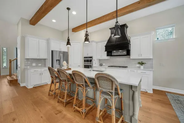 a kitchen with stainless steel appliances granite countertop a sink a stove a refrigerator and island with wooden floor