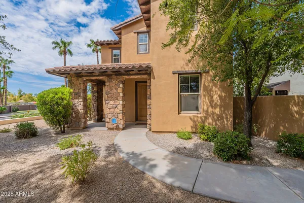 a view of a house with potted plants and a large tree