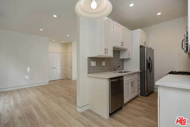 a kitchen with stainless steel appliances granite countertop a refrigerator a stove and a wooden floors