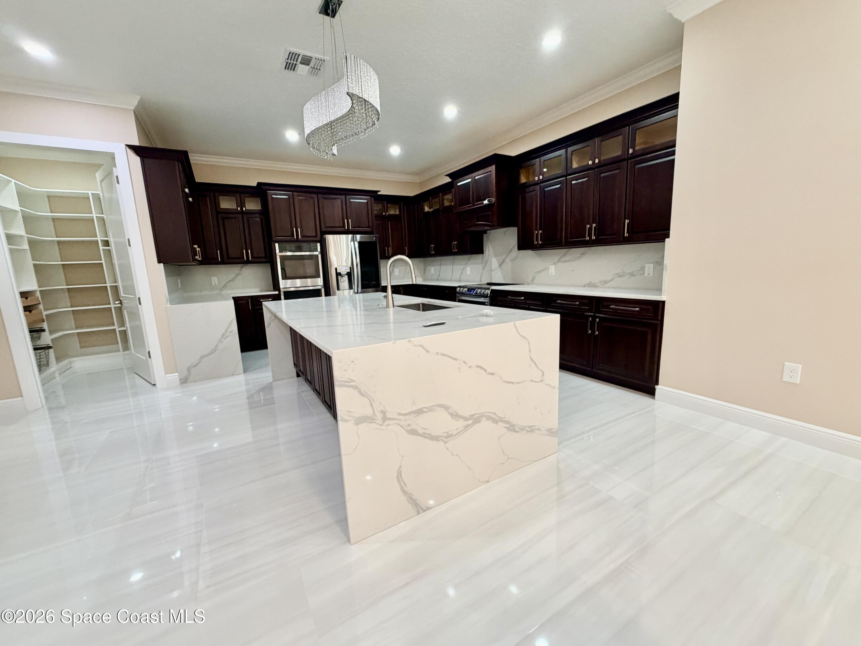 369 Tolley Avenue Melbourne, FL 32934 - Photo 11 of 33 a large white kitchen with stainless steel appliances kitchen island granite countertop a sink and a stove top oven with wooden floor
