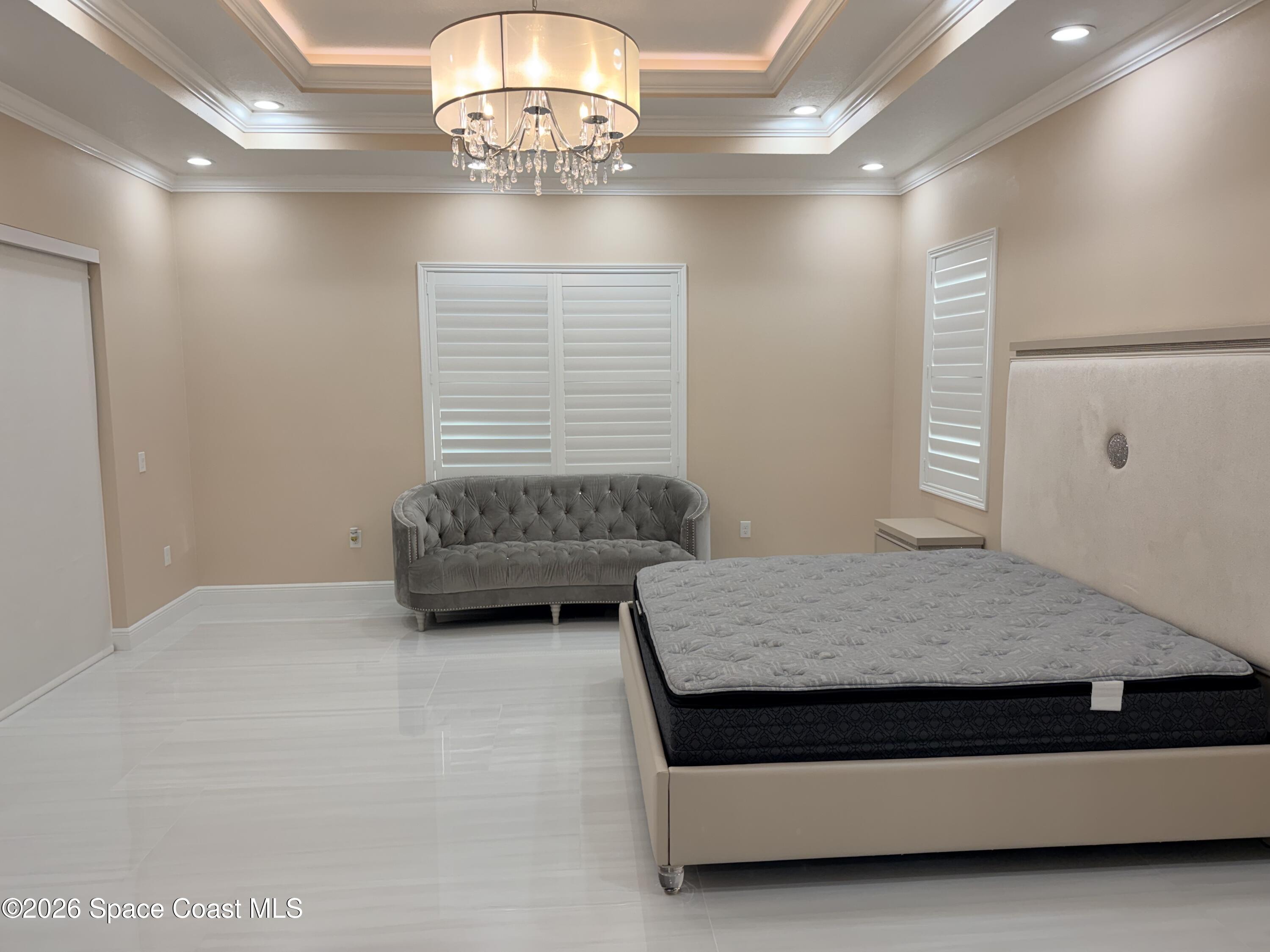 369 Tolley Avenue Melbourne, FL 32934 - Photo 17 of 33 a bedroom with a bed and a chandelier