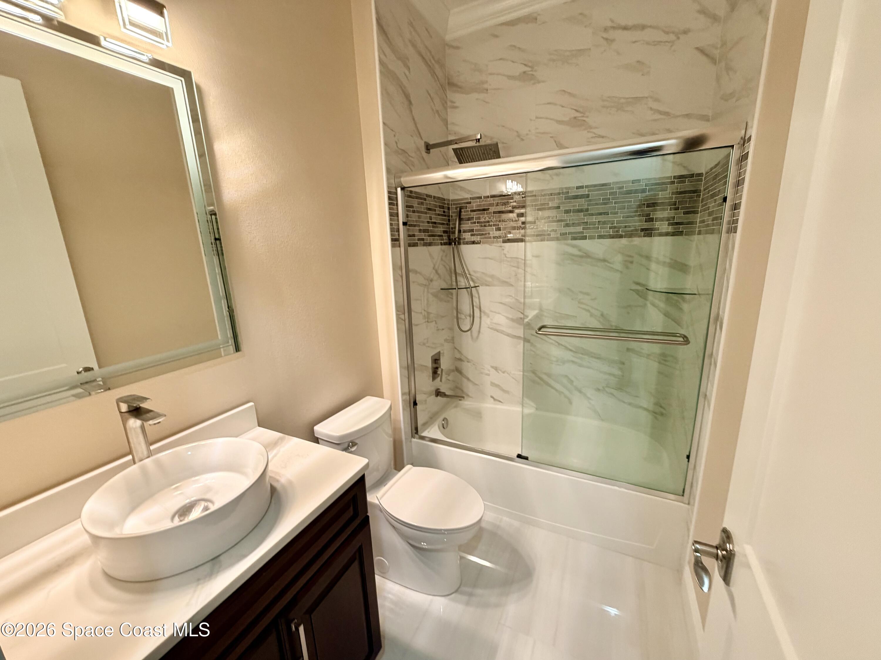 369 Tolley Avenue Melbourne, FL 32934 - Photo 27 of 33 a bathroom with a granite countertop sink toilet a mirror and shower