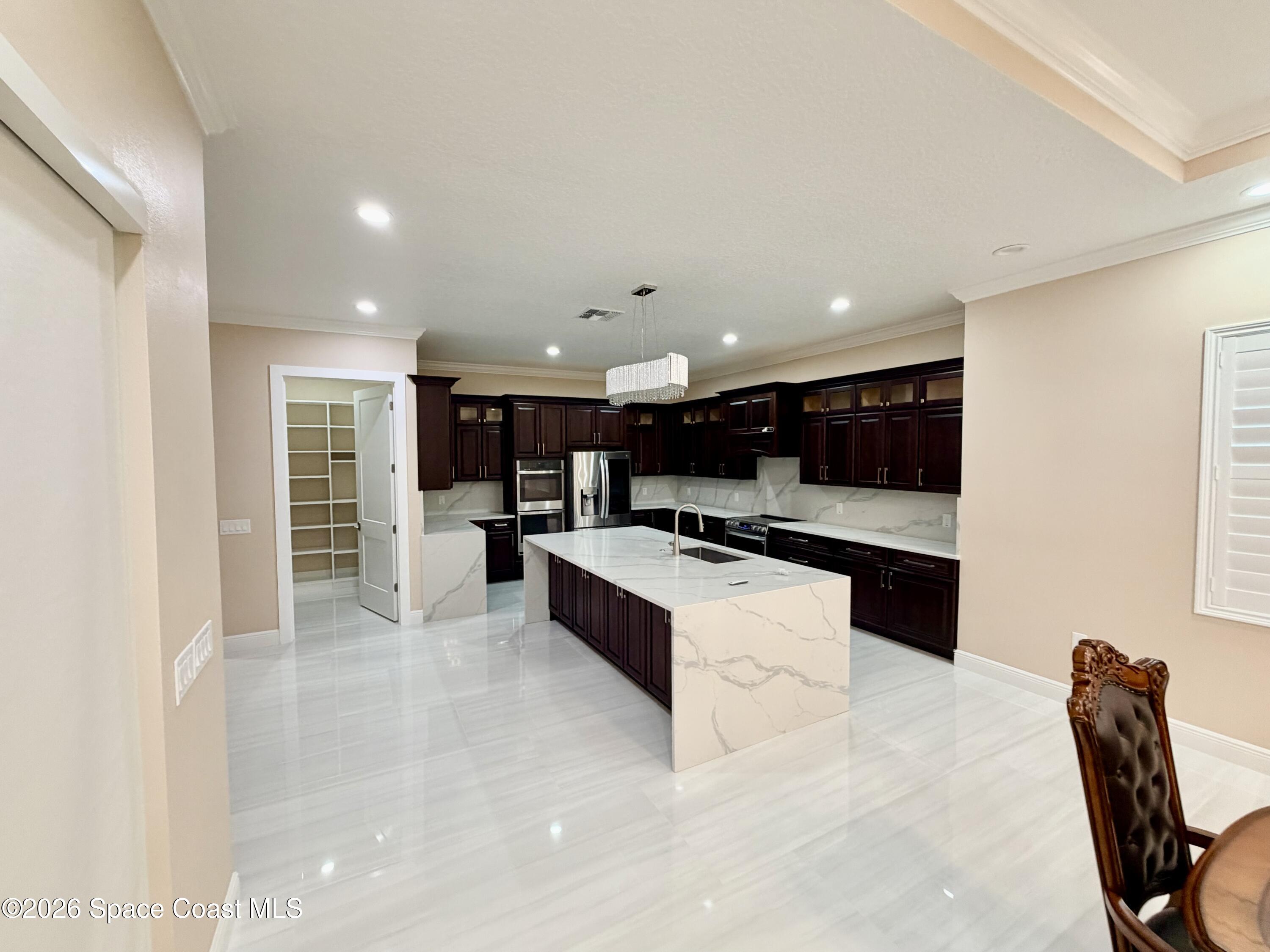 369 Tolley Avenue Melbourne, FL 32934 - Photo 10 of 33 a large white kitchen with stainless steel appliances kitchen island granite countertop a large counter top and view of living room