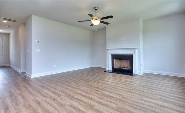 a view of an empty room with wooden floor and a fireplace