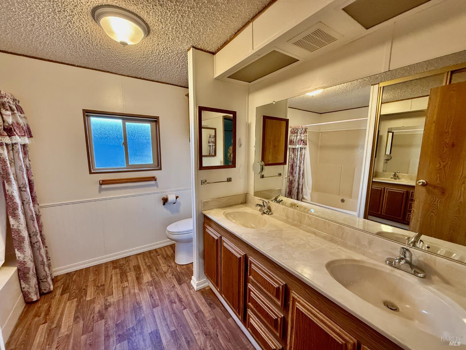 8148 D Street Windsor, CA 95492 - Photo 22 of 30 a bathroom with a granite countertop double vanity sink a mirror and wooden floor