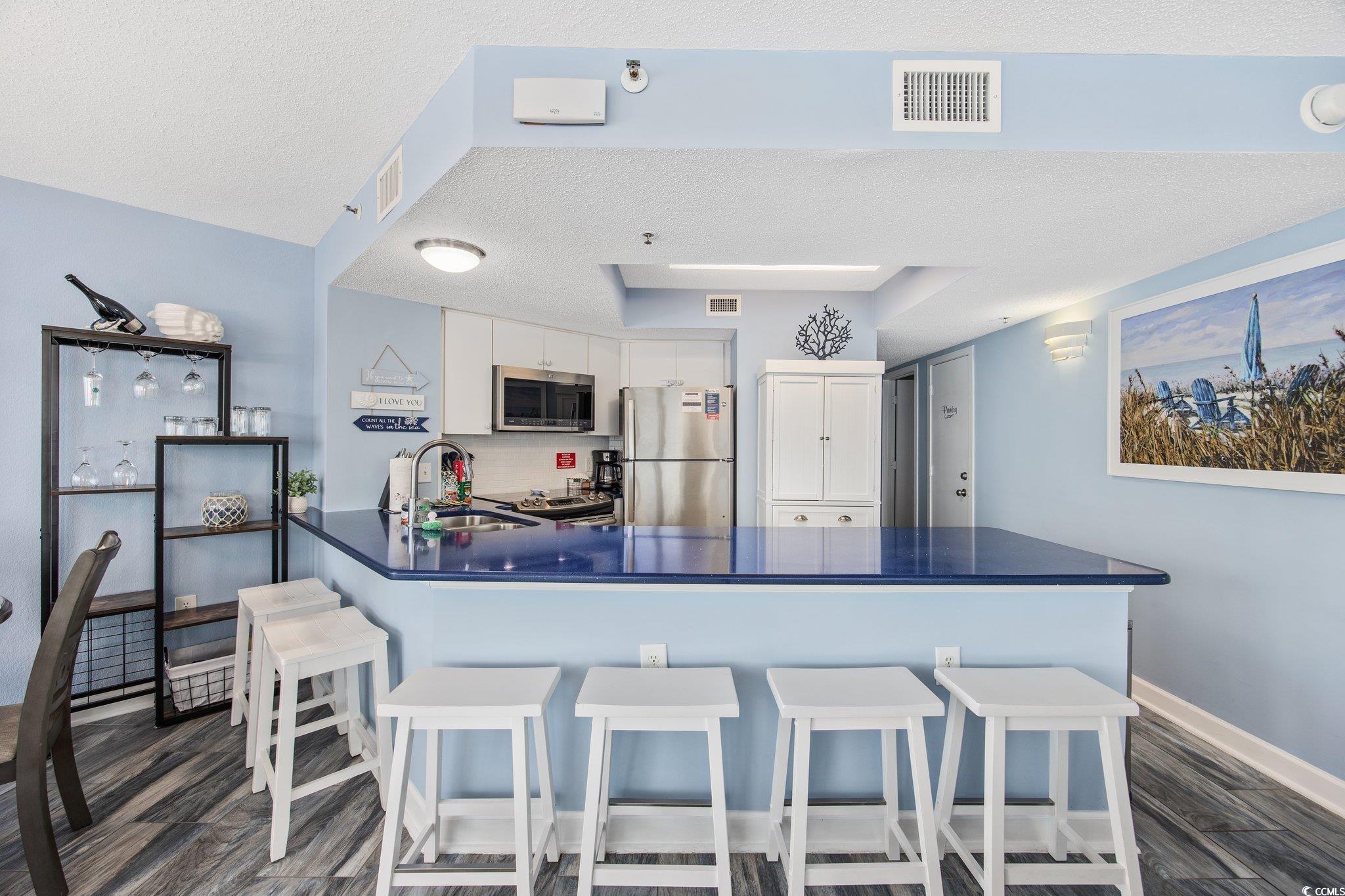 161 Seawatch Drive, Unit 1117 Myrtle Beach, SC 29572 - Photo 19 of 33 Kitchen with dark countertops, white cabinetry, a