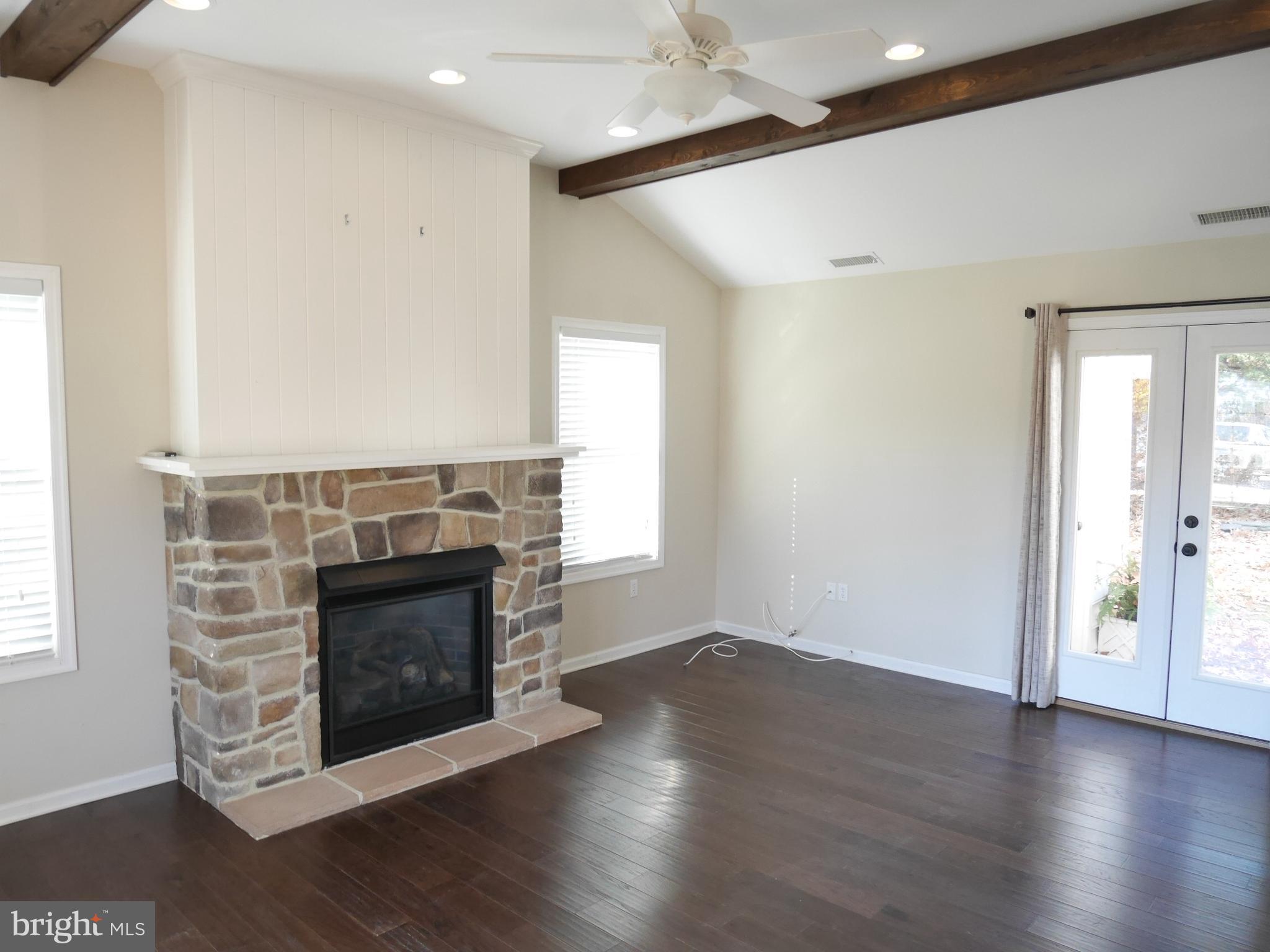 1705 Hambrooks Boulevard Cambridge, MD 21613 - Photo 4 of 22 an empty room with wooden floor a fireplace and windows