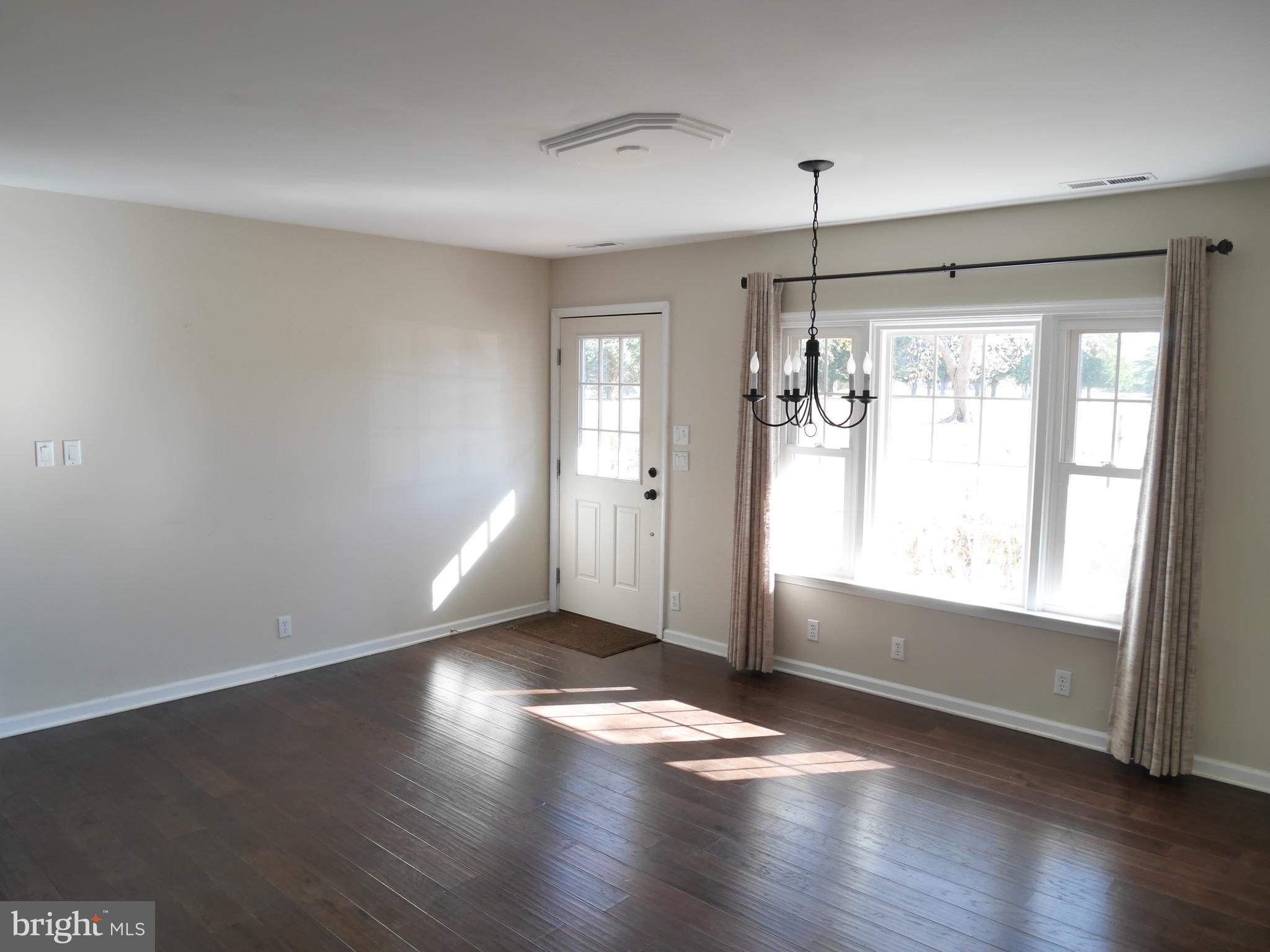 1705 Hambrooks Boulevard Cambridge, MD 21613 - Photo 6 of 22 a view of an empty room with wooden floor and a window