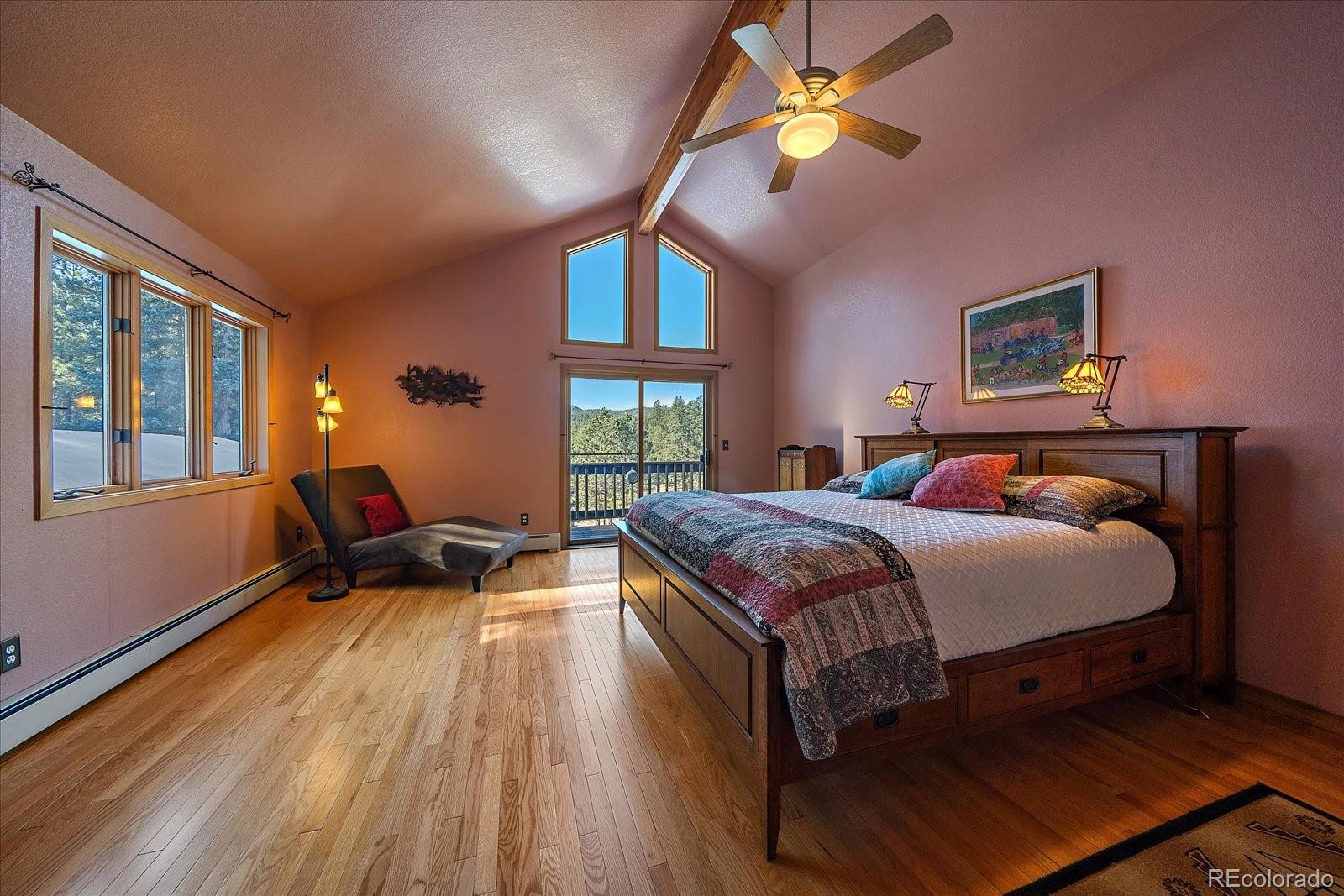 31196 Roberts Road Pine, CO 80470 - Photo 20 of 50 a spacious bedroom with a bed and a chandelier