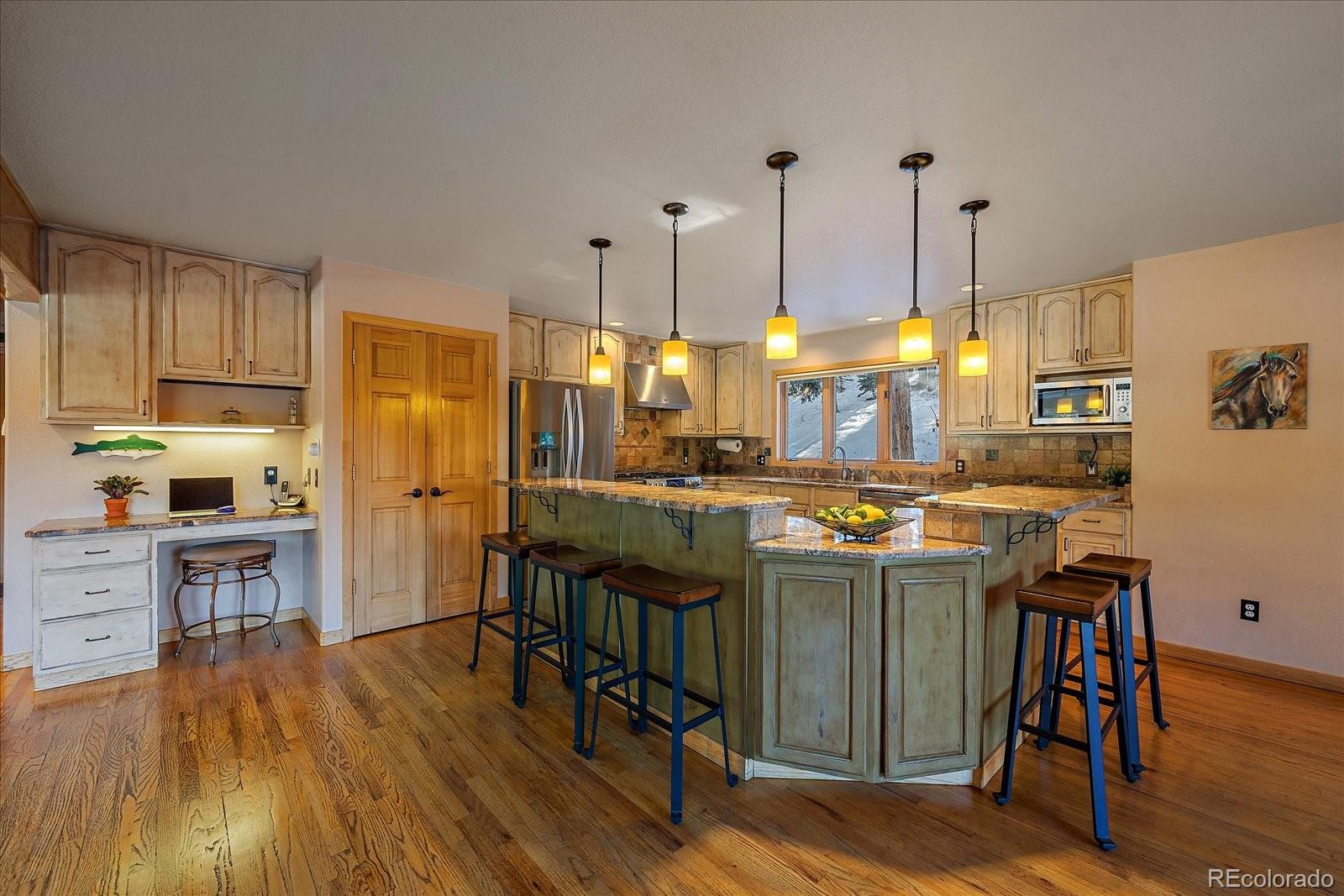 31196 Roberts Road Pine, CO 80470 - Photo 9 of 50 a kitchen with stainless steel appliances granite countertop a kitchen island a stove a refrigerator a sink a dining table and chairs with wooden floor