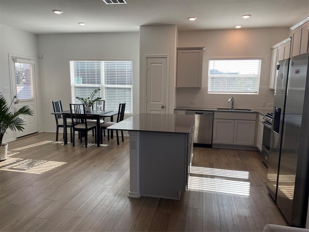 129 Starflower Cove Georgetown, TX 78628 - Photo 8 of 31 Kitchen with stainless steel appliances, tasteful backsplash, gray cabinetry, a center island, and dark wood-style floors