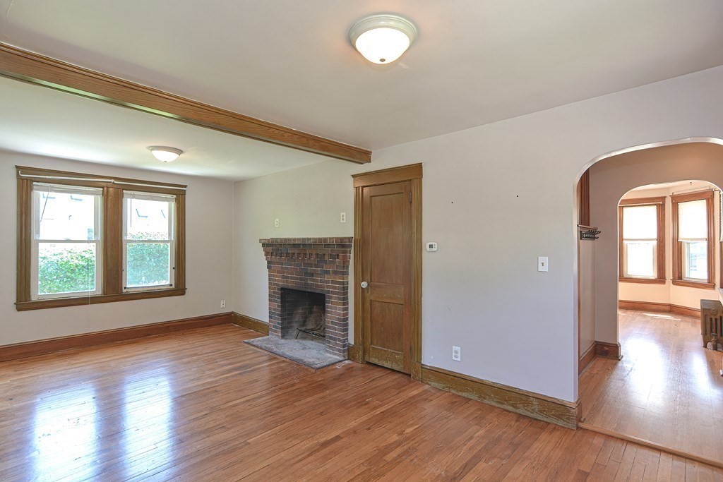 228 Pond Street Natick, MA 01760 - Photo 8 of 36 an empty room with wooden floor fireplace and windows