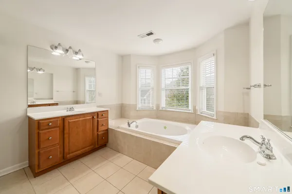 a spacious bathroom with a tub sink and mirror