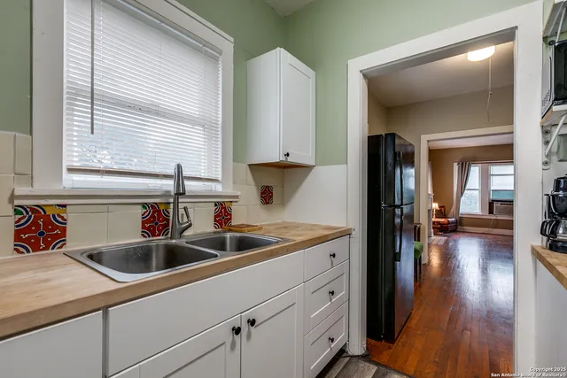 a kitchen that has a sink and a stove with wooden floor