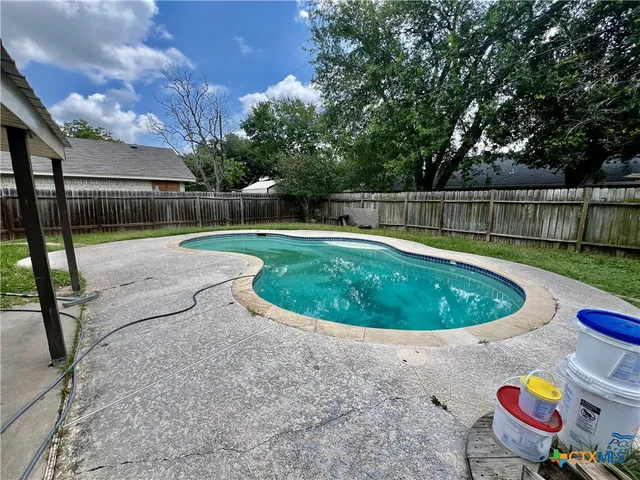 a view of a backyard with swimming pool and wooden fence