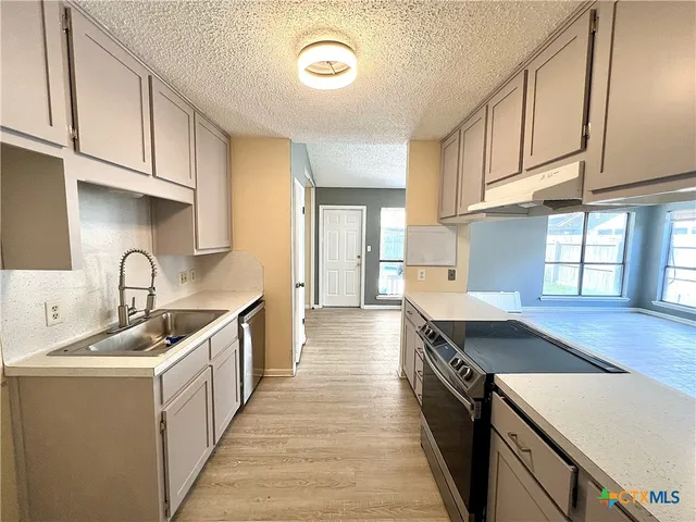 a kitchen with stainless steel appliances granite countertop a sink stove and cabinets