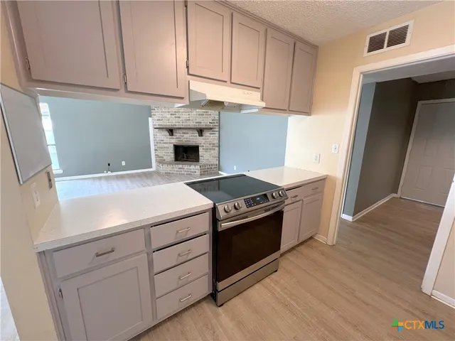 a kitchen with granite countertop white cabinets and stainless steel appliances