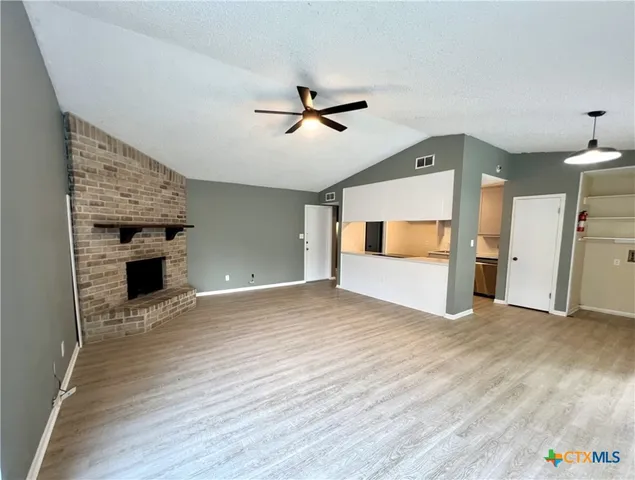 a view of empty room with wooden floor and fireplace