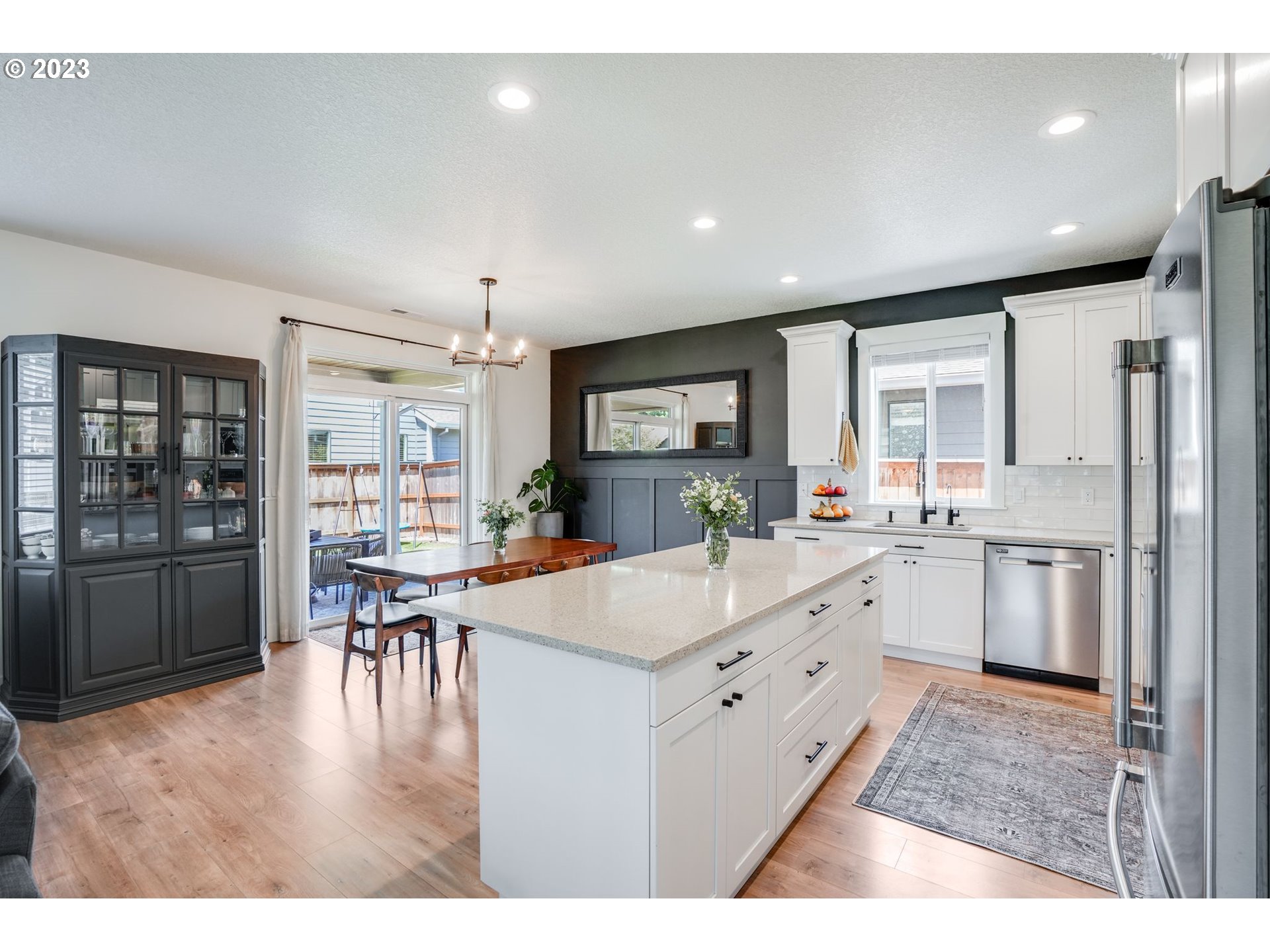 2889 4th Street Hubbard, OR 97032 - Photo 11 of 37 a large white kitchen with granite countertop a stove a sink a dining table and chairs