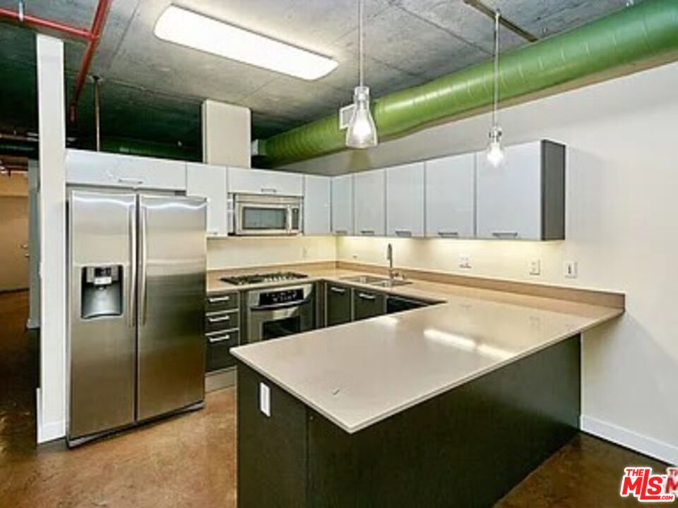 645 West 9th Street, Unit 240 Los Angeles, CA 90015 - Photo 5 of 25 a kitchen with stainless steel appliances a table chairs and a refrigerator