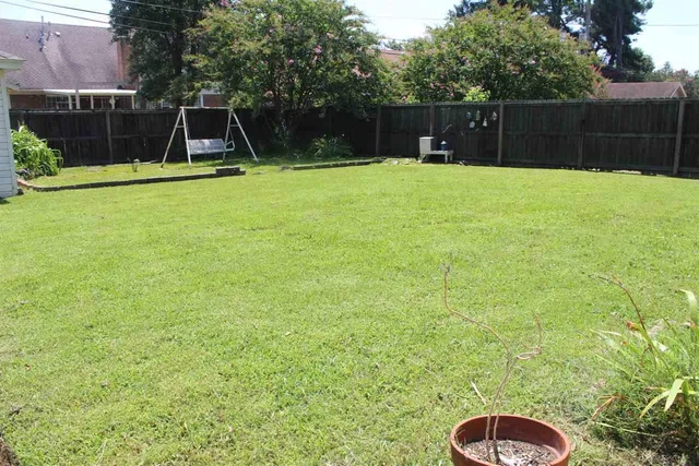 a backyard of a house with swing and plants