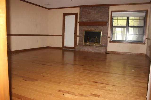 a view of empty room with wooden floor and fireplace