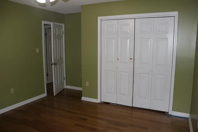 an empty room with wooden floor and closet area