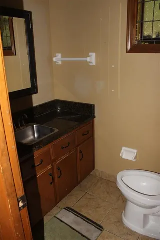 a bathroom with a granite countertop sink a toilet and a mirror