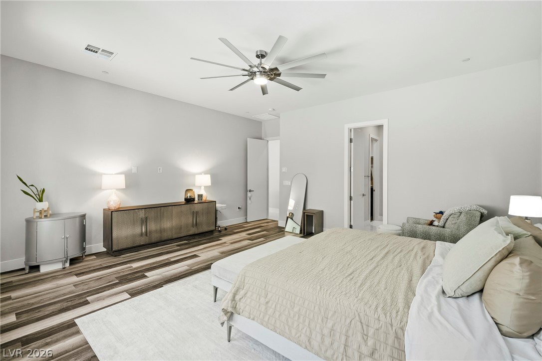 45 Garibaldi Way Henderson, NV 89011 - Photo 10 of 74 A well-lit bedroom featuring a striking ceiling fan and rich hardwood-style flooring, offering a perfect retreat.