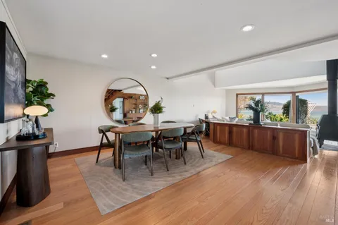 a kitchen with stainless steel appliances granite countertop a stove top oven a dining table and chairs with wooden floor