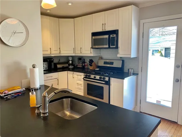 a kitchen with granite countertop a sink a stove and a microwave