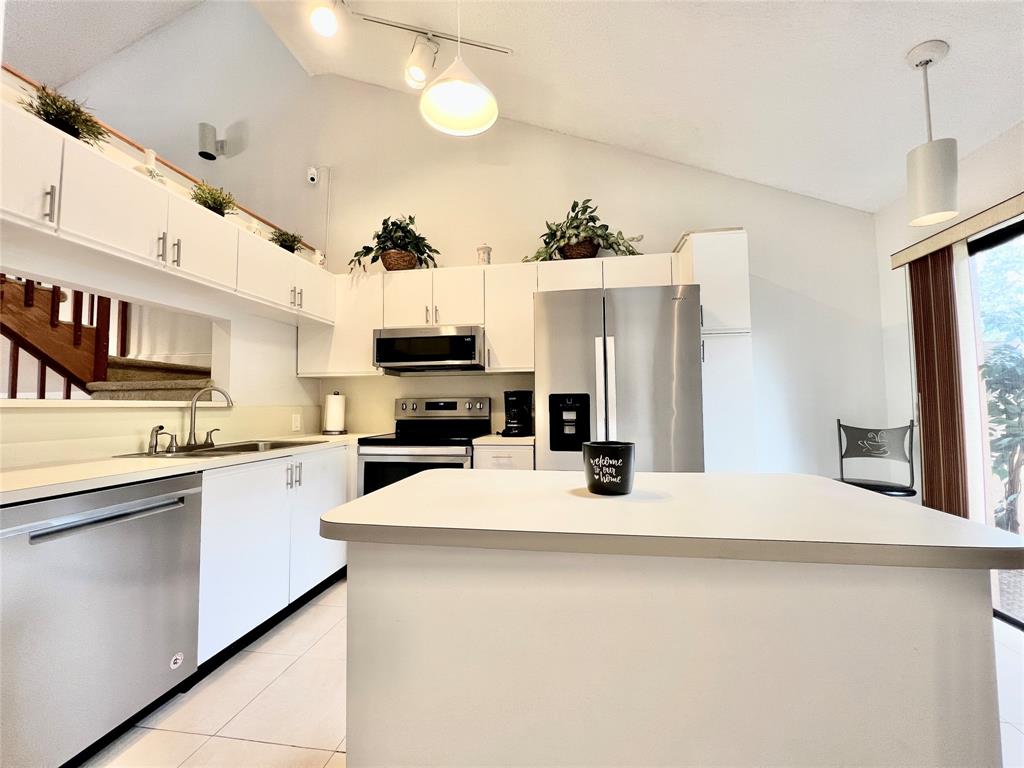 7750 Northwest 79th Avenue, Unit H5 Tamarac, FL 33321 - Photo 11 of 28 a kitchen with stainless steel appliances a stove refrigerator sink and microwave